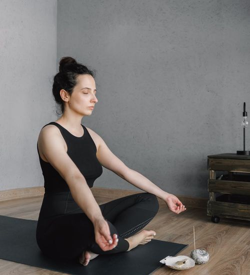 Smiling person unrolling a yoga mat in a bright, welcoming room.